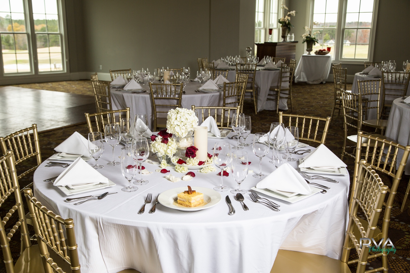 The ballroom at The Estate at Independence, set for a wedding with gold chiavari chairs and floor-to-ceiling course views.